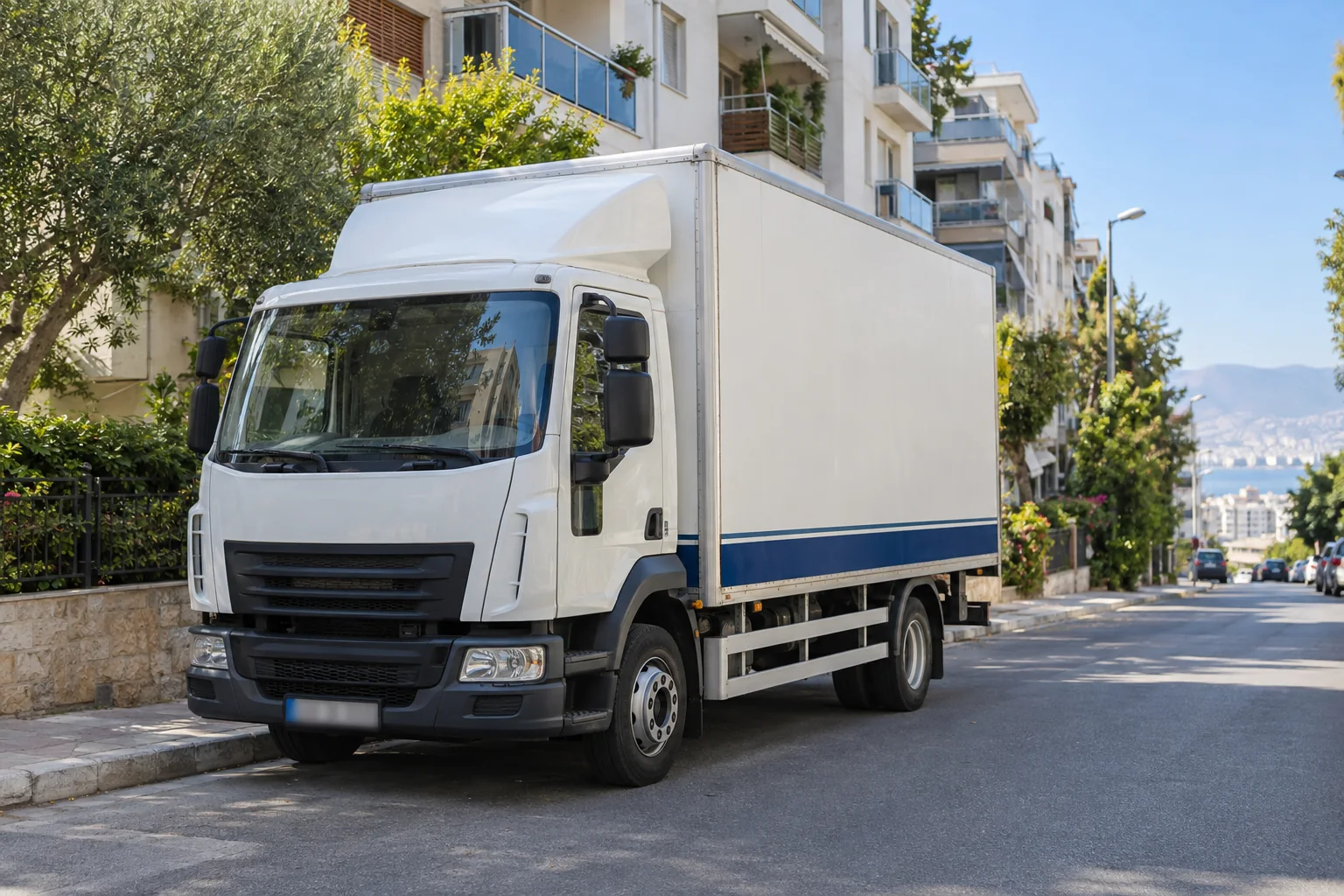 Apartmanların bulunduğu eğimli bir sokakta duran beyaz ve mavi kapalı kasa kamyonun temsili TaşınmaTick sahnesi